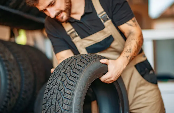 Employee in tyre service with car tyres